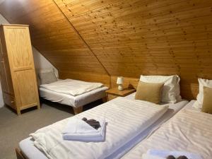 a room with two beds and a wooden ceiling at Pension MÍŠA in Velká Úpa