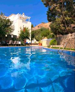 a swimming pool with blue water in front of a house at Castelli Retreat in Spetses