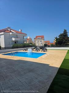a swimming pool with tables and benches in a yard at ANTODO Batista in Novalja