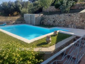 a swimming pool in a yard with a stone wall at KaraA'mare in San Teodoro +10 photos