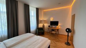 ein Hotelzimmer mit Bett und Schreibtisch mit Fernseher in der Unterkunft Kolbeck Rooms in Wien