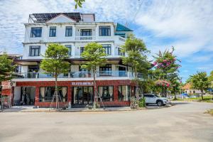 a white building with trees in front of it at Celestia Hue Villa in Hue