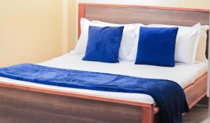 a bed with blue and white pillows on it at Countryside Apartment 1 in Kiambu