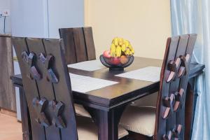 a table with a bowl of bananas and a bowl of fruit at Countryside Apartment 1 in Kiambu