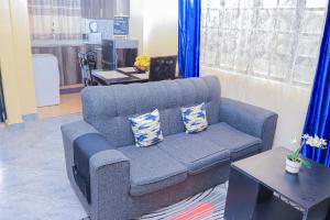 a living room with a blue couch and a table at Countryside Apartment 1 in Kiambu +13 photos