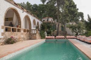 a swimming pool in front of a house with chairs at Villa Dora in Jávea