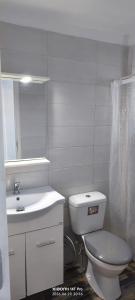 a white bathroom with a toilet and a sink at Green Boat House in Skala