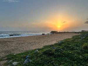 a beach with the sun setting on the horizon at Athulya Tropical Paradise in Paravūr