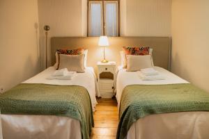 two twin beds in a room with a lamp at Provesende Douro Villas - Casa Principal in Provesende +17 photos