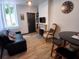 a living room with a couch and a clock on the wall at Apartment with a garden in Moulins