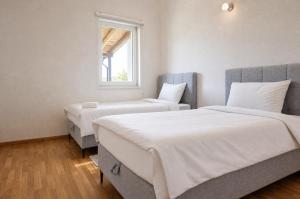two beds in a room with a window at Sarajevo Resort Gestoria in Hadžići