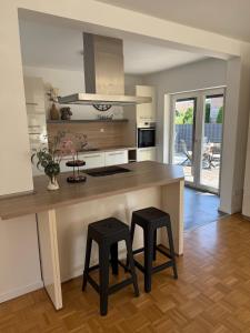 a kitchen with a large island with two black stools at Karolinger Stay in Emmerich