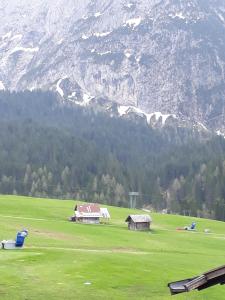 a green field with houses in front of a mountain at Appartamento centrale Sappada in Sappada +6 photos