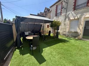 a patio with a table and chairs on the grass at le nid gourmand in Andryes