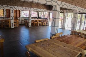 a dining room with tables and chairs and windows at Cabañas sierra grande in Creel