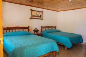 two beds in a room with wooden ceilings at Cabañas sierra grande in Creel