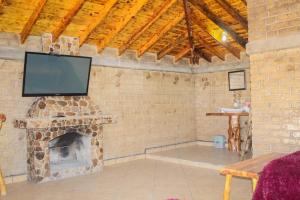a living room with a brick fireplace with a flat screen tv at Cabañas sierra grande in Creel