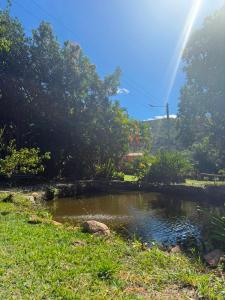a pond in the grass with a rainbow in the background at Pousada e Camping Sá Zabé in Rio de Contas