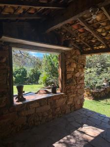 a window in a stone building with a view of a yard at Pousada e Camping Sá Zabé in Rio de Contas