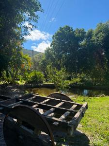 a wooden bench sitting in the grass next to a pond at Pousada e Camping Sá Zabé in Rio de Contas