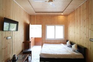 a bedroom with a bed in a room with wooden walls at The Great Hill View Hotel in Phata