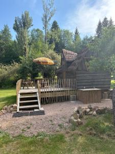 a wooden cabin with an umbrella and a wooden staircase at La cabane de Moïra in Xertigny