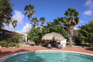 a swimming pool in a yard with palm trees at Caribbean Court E1 in Kralendijk