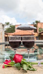 two glasses of wine and a rose on a table at Pousada Yanah in Pirenópolis