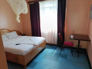 a bedroom with a bed and a desk and a window at City Brisa cbd in Nairobi