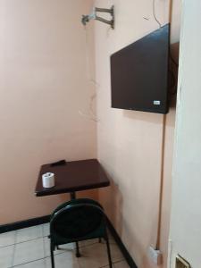 a small table with a chair and a television on a wall at City Brisa cbd in Nairobi