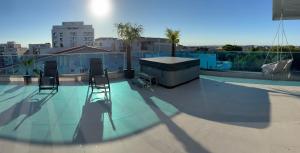 a swimming pool with two chairs and a table on a roof at Penthouse Rico in Eforie Nord