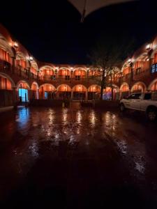 a lit up building at night with a parking lot at Hotel Estancia Bugambilias in San Diego de la Unión