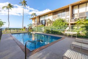 a swimming pool in front of a building with palm trees at Makani A Kai Resort A-3 in Wailuku