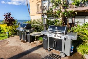 two bbqs and a grill and a stool next to a building at Makani A Kai Resort A-3 in Wailuku