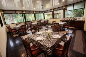 a dining room with tables and chairs and windows at Misty D Silver in Munnar