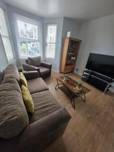 a living room with a couch and a flat screen tv at The Coastal Nest in Folkestone