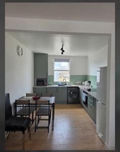 a kitchen with a table and chairs and a kitchen with green at The Coastal Nest in Folkestone