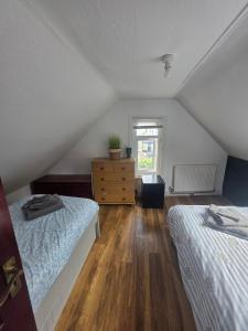 a attic bedroom with two beds and a dresser at The Coastal Nest in Folkestone