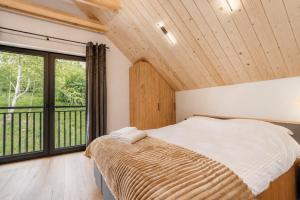 a bedroom with a bed and a large window at SenWood House in Zubrzyca Dolna
