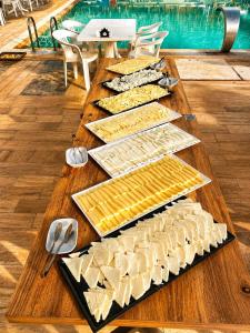 a long wooden table with several different types of cheese at Grand Rimedya Hotel in Karabağ