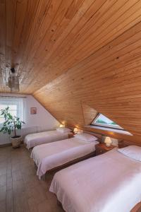 a row of beds in a room with a wooden ceiling at B&B Na Kluk in Idrija