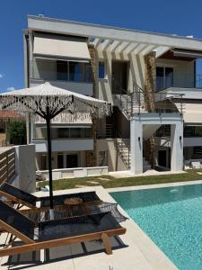 a villa with a swimming pool and an umbrella at Azulic Suites Nikiti in Nikiti
