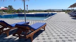a couple of lounge chairs next to a swimming pool at IL Paradiso in Kavajë