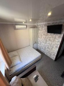 a small room with a bed and a tv at Гостевой дом Надежда in Zatoka