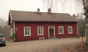 ein rotes Haus mit einer Bank davor in der Unterkunft Ljungås Gamla Skola in Askersund