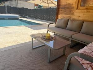 a couch and a coffee table next to a pool at Chalet en bois indépendant, terrasse et accès piscine in Montret +10 photos