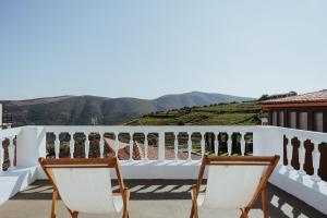 a balcony with two chairs and a view of mountains at Provesende Douro Villas -Pateo Douro in Provesende