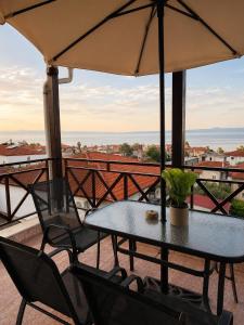 a table and chairs on a balcony with an umbrella at Este Luxury Apartments in Kriopigi