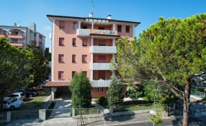 a pink building with trees in front of it at Orchidea in Bibione