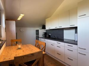 a kitchen with a wooden table and white cabinets at Ferienwohnung in Burhave in Burhave